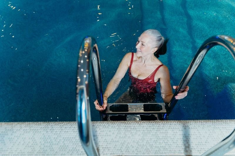 Woman with limited mobility using a pool ladder in supportive swimwear