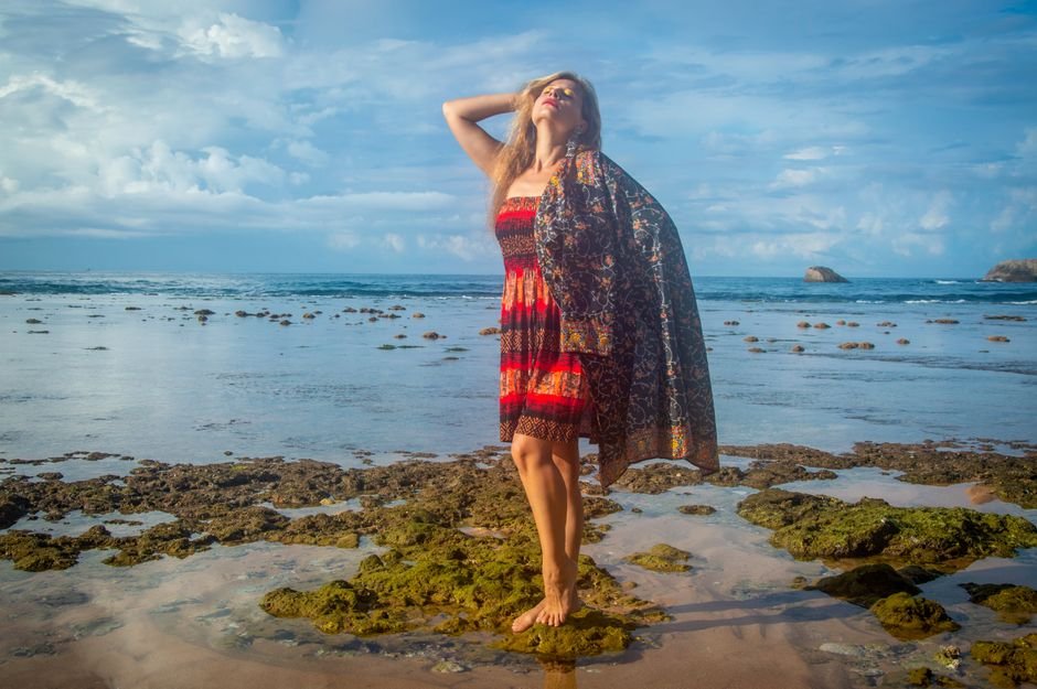 Woman in colorful dress embracing beach vibes with joyful expression.