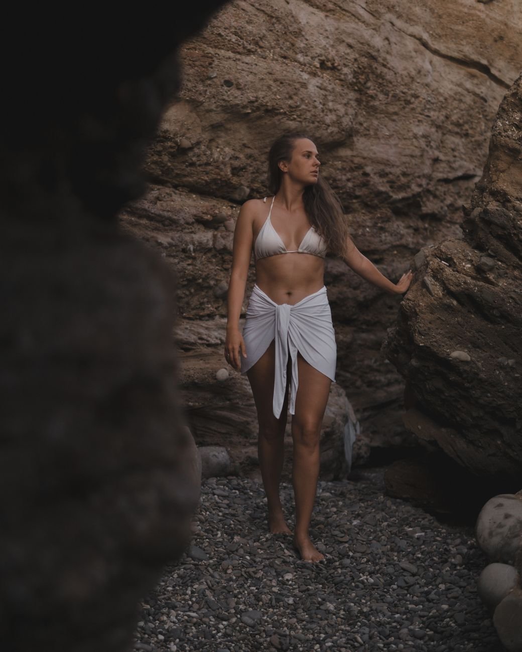 Woman wearing a white bikini and sarong wrap standing outdoors