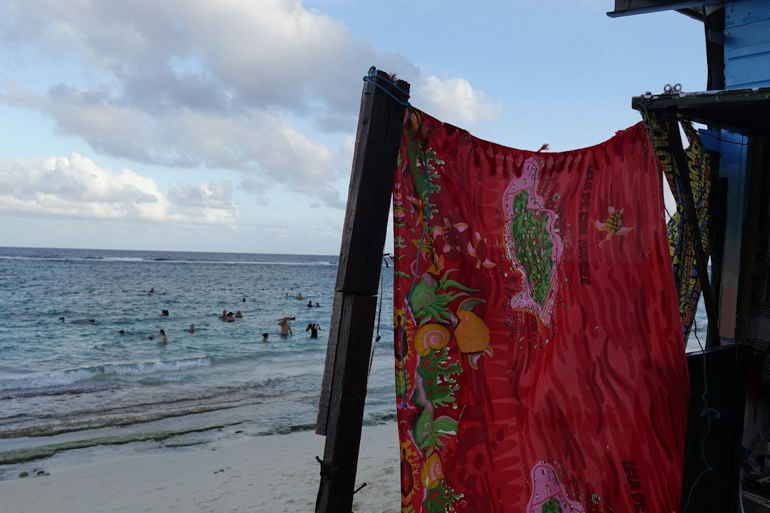 Red fabric on beach with people swimming in ocean