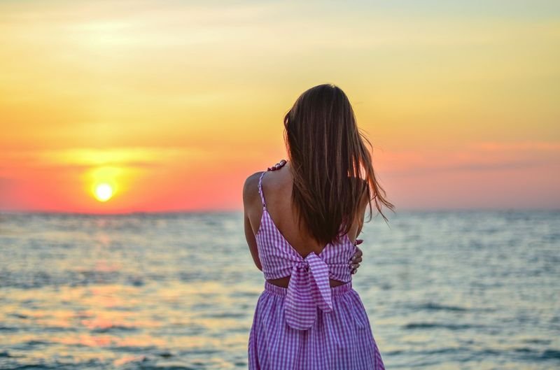 Woman tying a sarong wrap dress knot securely at the waist on the beach