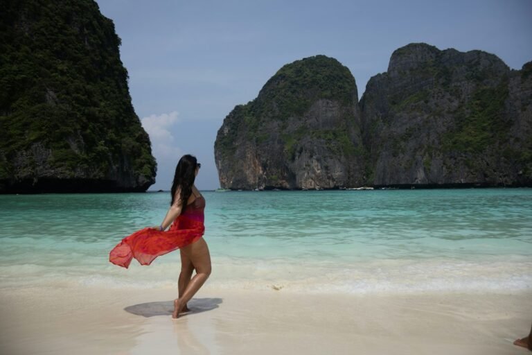 A vibrant shot of a woman posing confidently in red swimwear at the stunning Maya Bay, Thailand. The turquoise waters, white