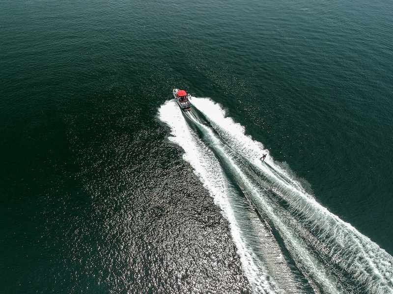 Aerial view of a tow boat pulling a water skier across the wake