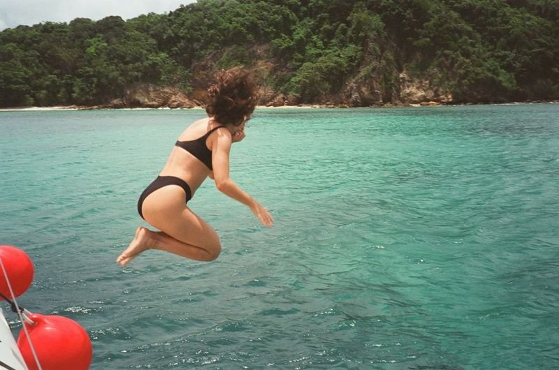 Woman in a swimsuit jumping off a boat into the water
