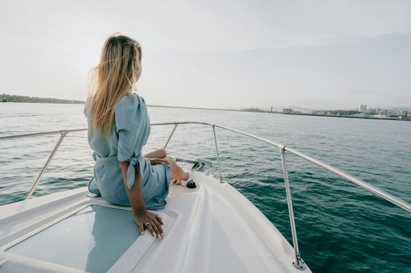 Woman in a light cover-up on the bow of a boat as the wind picks up