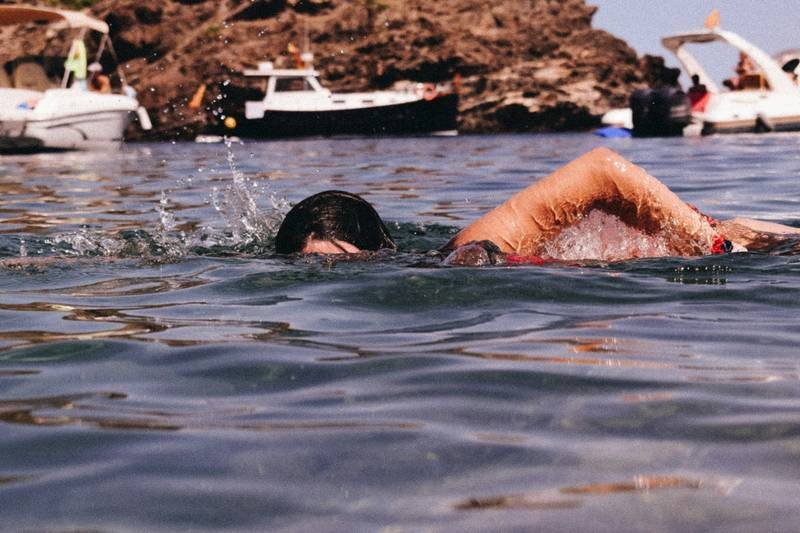 woman wearing black swim goggles swimming in the ocean