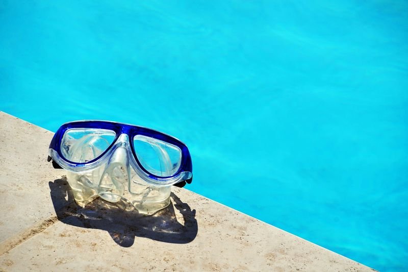blue swim goggles resting poolside in the sun