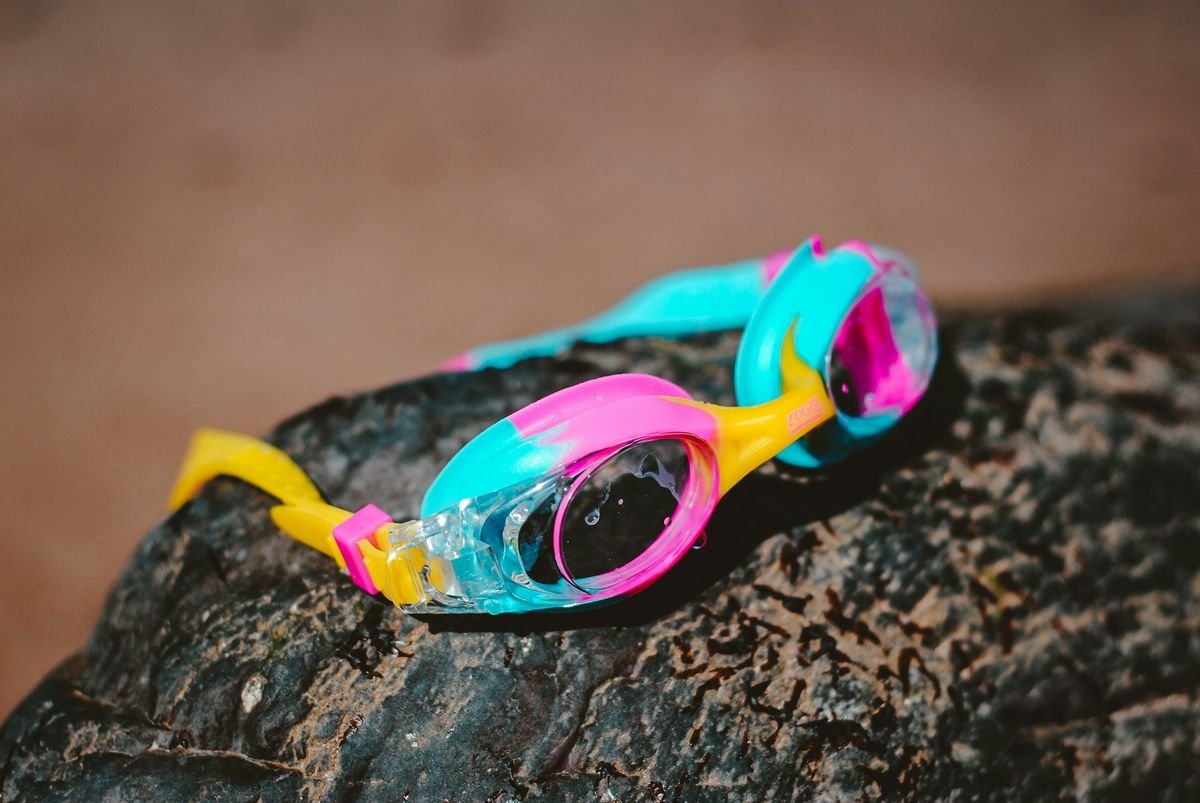 Swim goggles resting on a rock at the beach