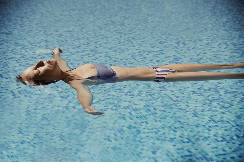 Woman floating in a pool, cooling off during a menopause hot flash