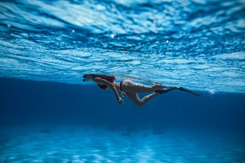 swimmer wearing a bikini with fins underwater, the side-tie design most likely to shift during a duck dive