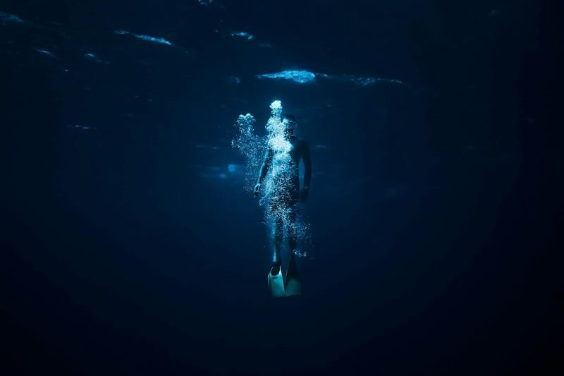 freediver descending headfirst during a duck dive wearing swimwear built for freediving