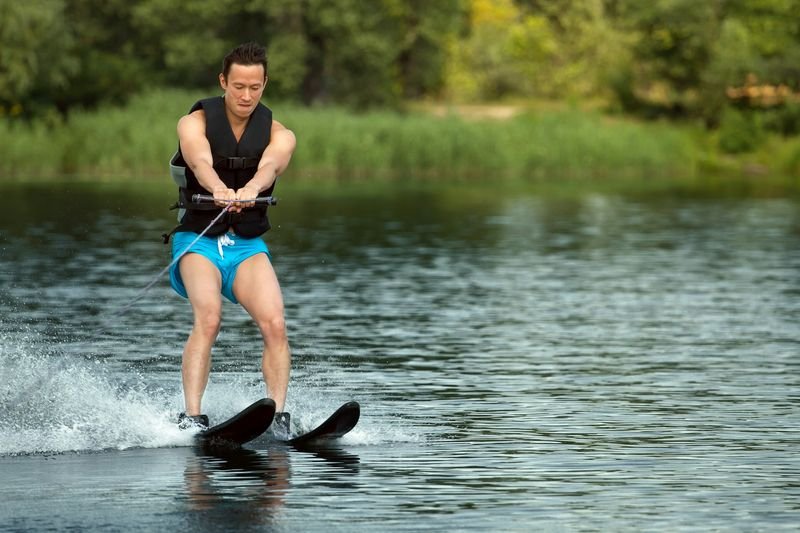 Water skier doing a deep-water start in a one-piece swimsuit and life vest