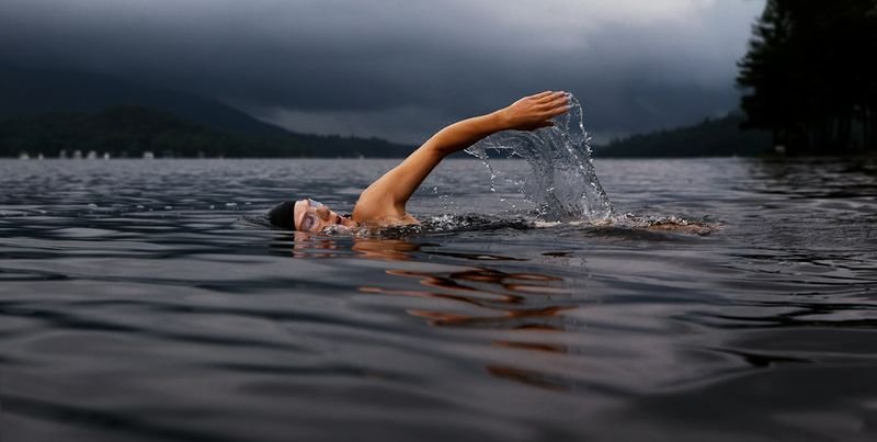 Open water swimmer wearing a bright swim cap mid-stroke