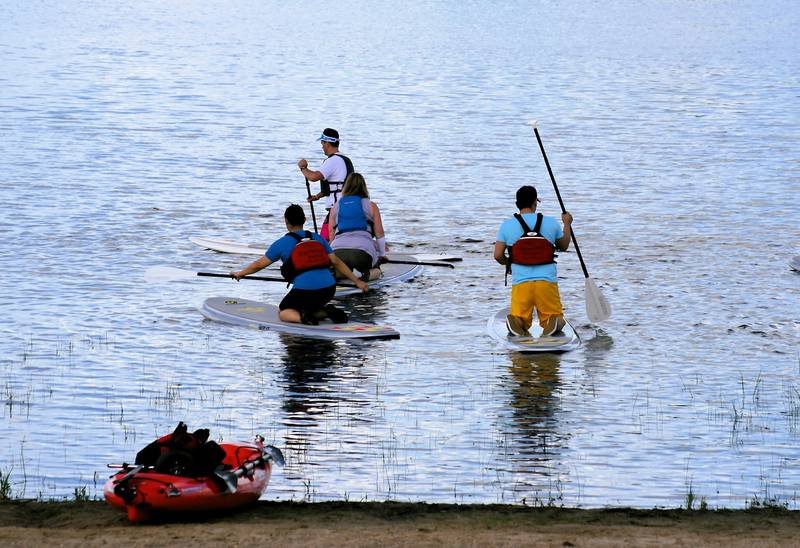 Paddleboarders wearing life jackets for water safety on a lake