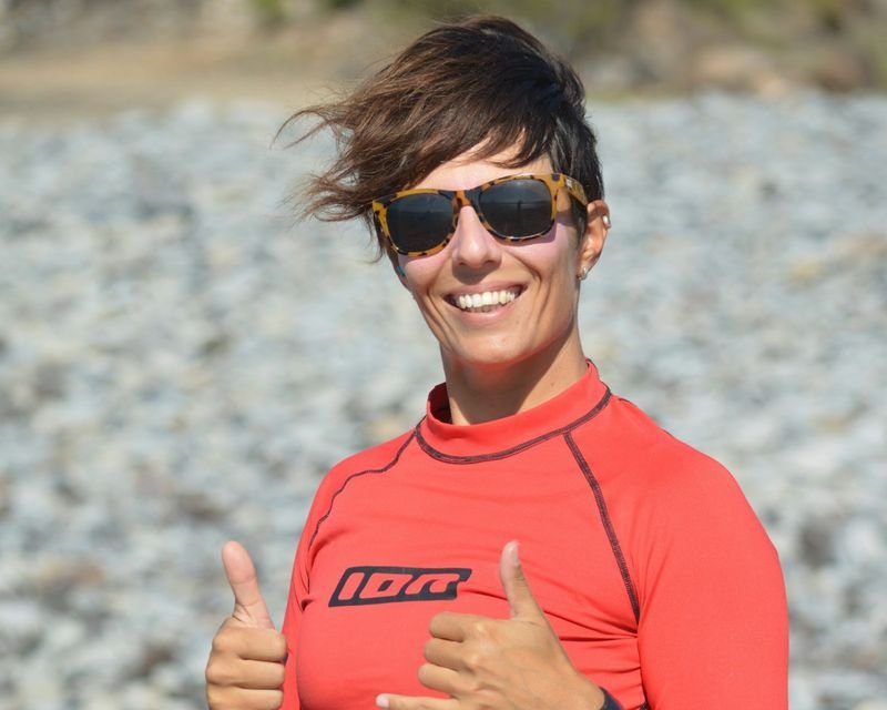 woman in rash guard snorkeling swimwear giving thumbs up on rocky beach