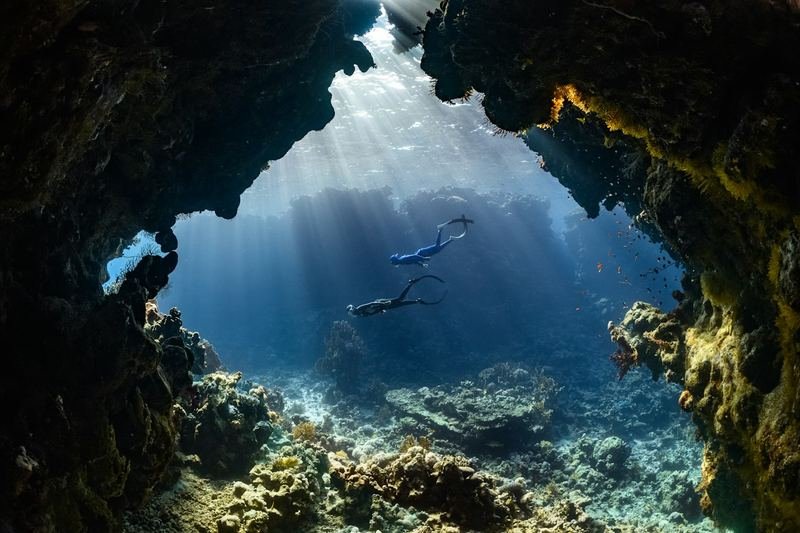 scuba diver in swimwear exploring an underwater reef cave