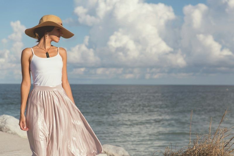 Woman walking along the beach wearing a straw sun hat