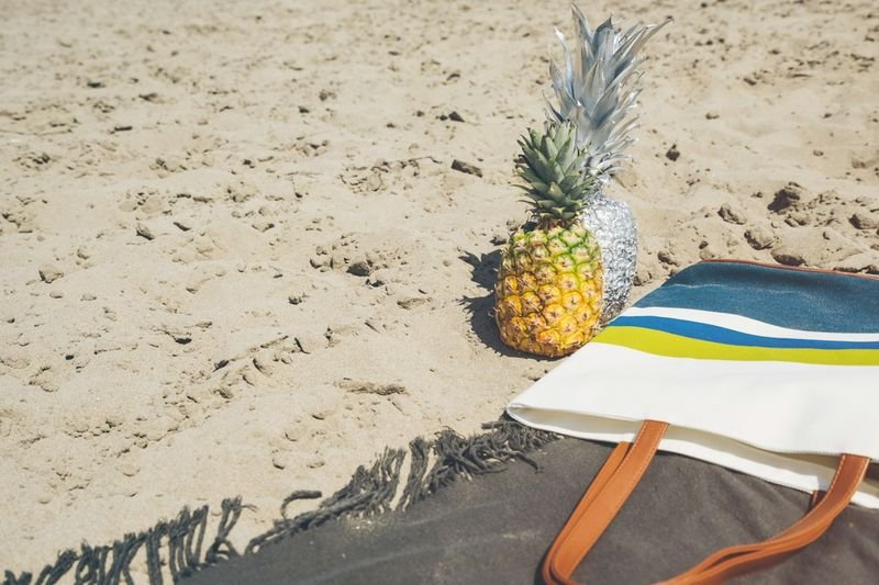Straw beach tote bag set on the sand next to a beach towel