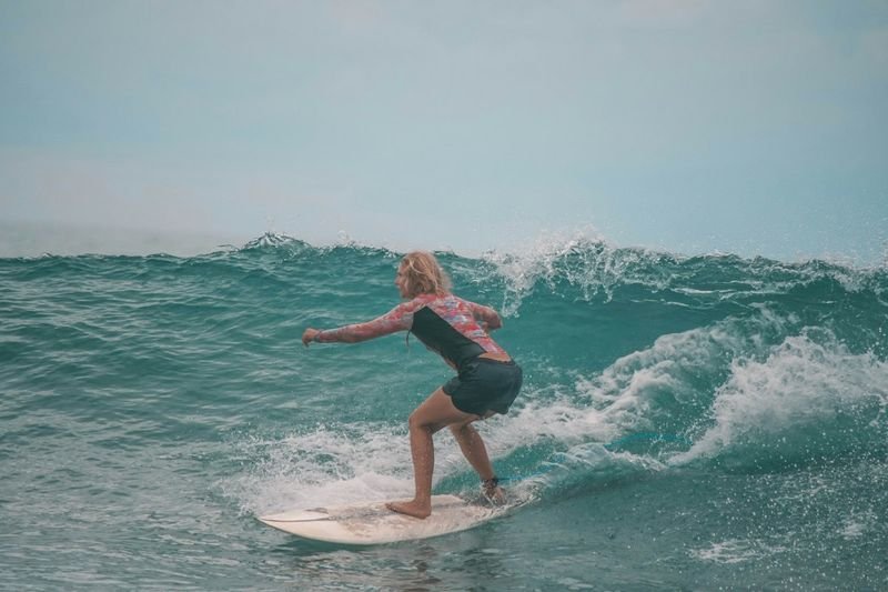 Woman wearing surfing swimwear riding a wave on a surfboard