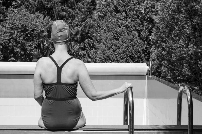 Woman wearing a swim cap and goggles relaxing poolside