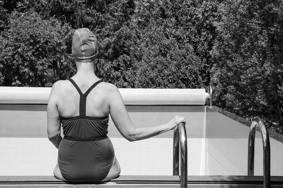 Woman wearing a swim cap and goggles relaxing poolside