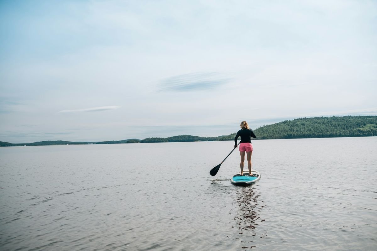 Woman wearing secure athletic swimwear while stand up paddleboarding