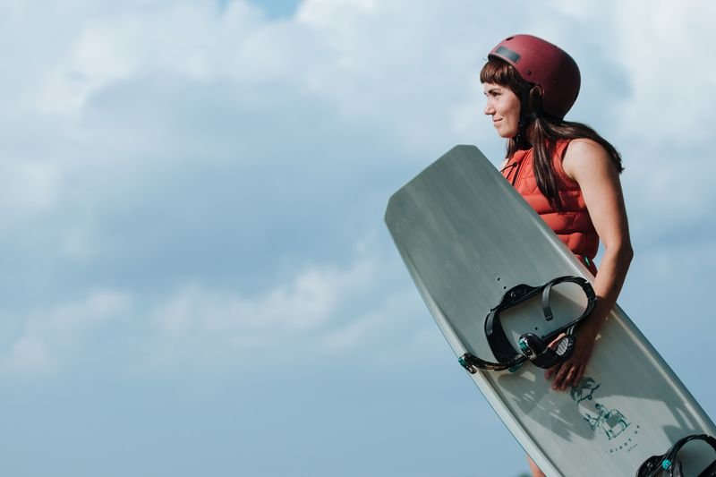 Wakeboarder in life vest holding wakeboarding swimwear and board with bindings