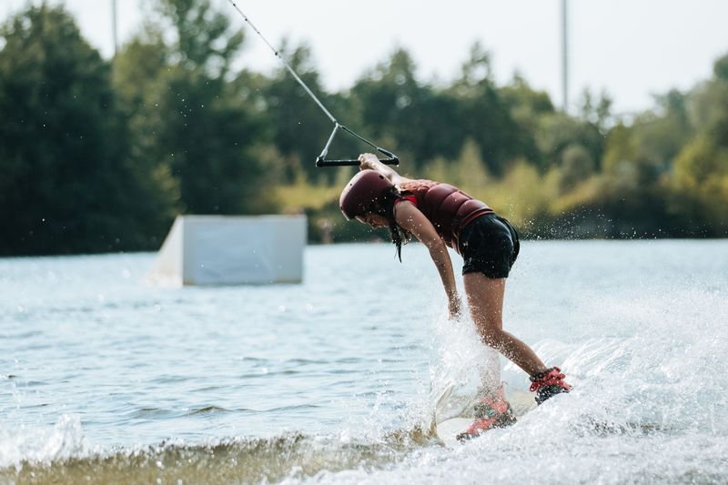 Wakeboarder in racerback wakeboarding swimwear riding through wake spray