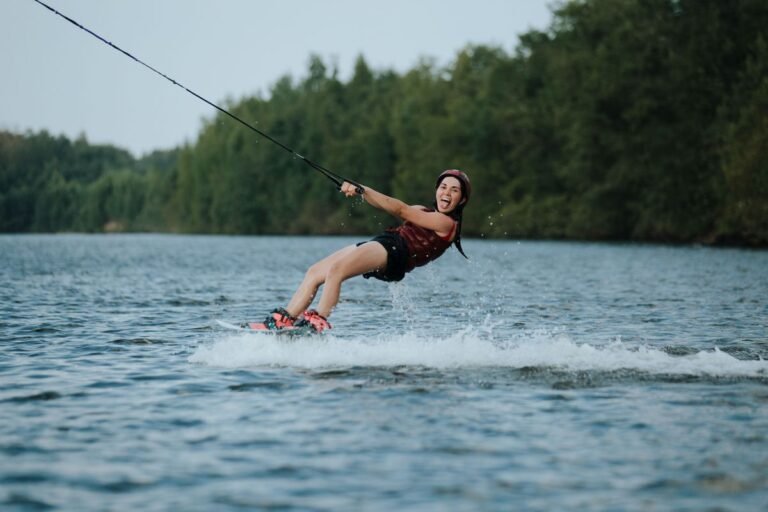 Woman in athletic swimsuit wakeboarding behind a boat on a lake