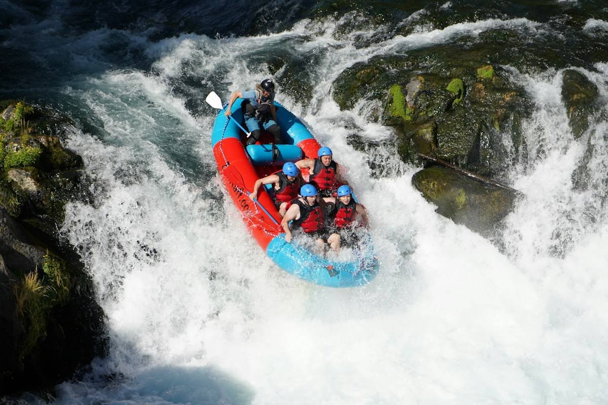 woman in whitewater rafting swimwear with life jacket on rocky river rapids