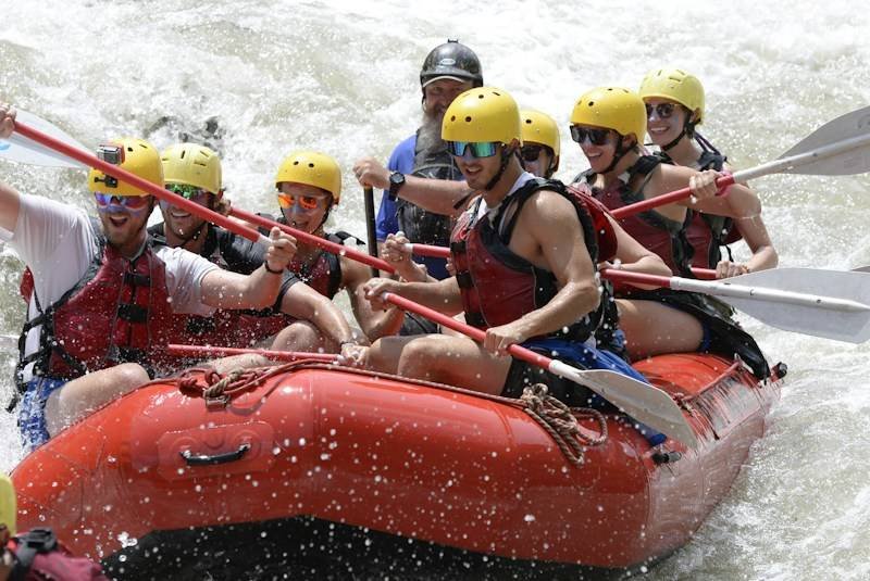 rafters wearing secure life vests and helmets over swimwear hitting rapids