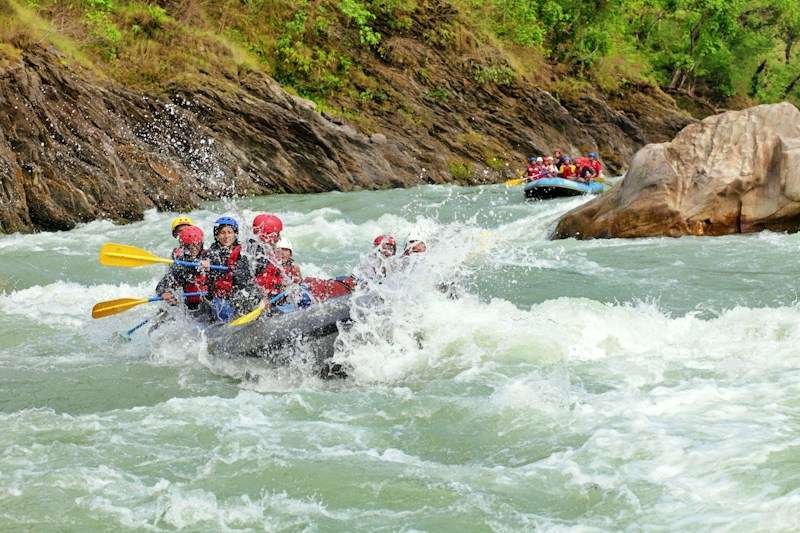 group in rafting swimwear hitting splash on river rapids